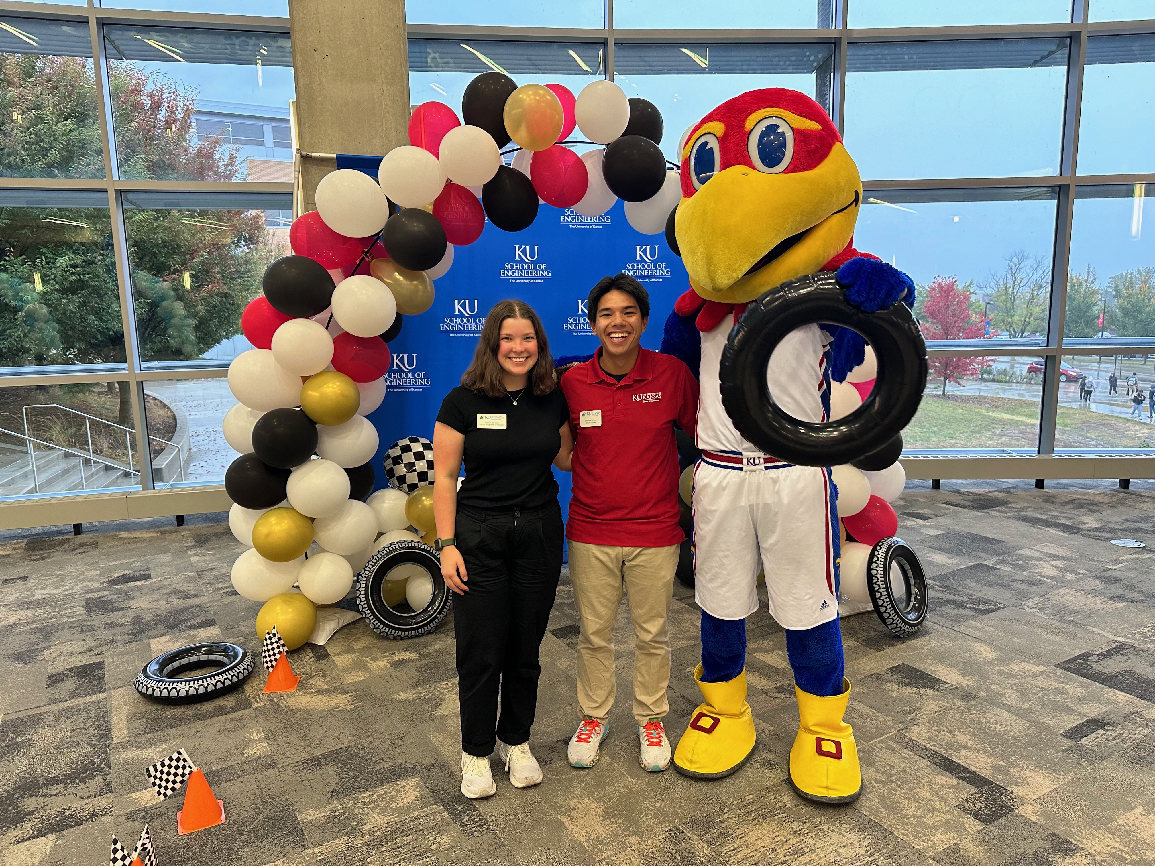 KU engineering student Andrew Reyes poses with the Jayhawk mascot and another student at a High School Design Competition event, planned and hosted by KU SELF fellows.