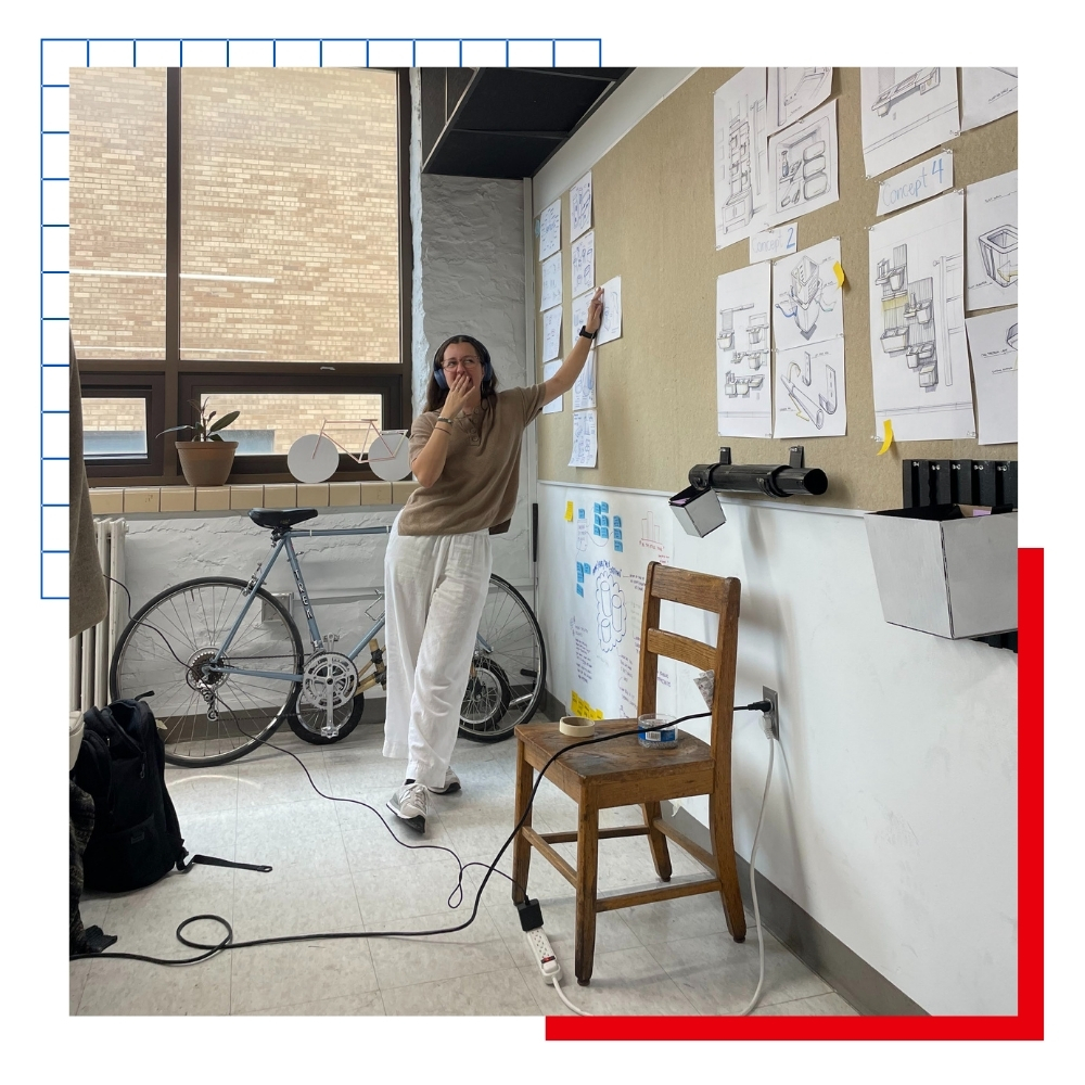 A KU Industrial Design Degree student leans against a wall in a studio classroom environment.
