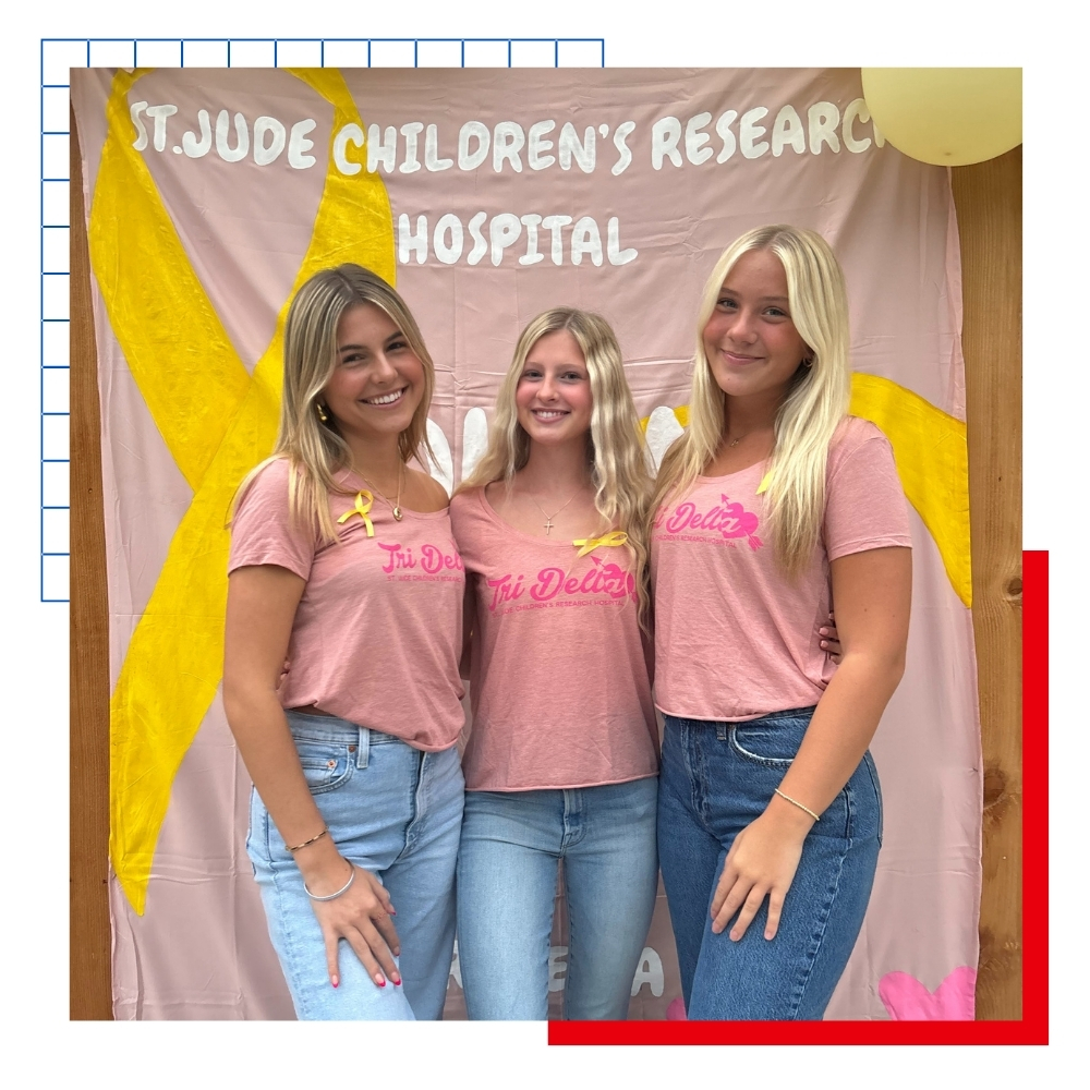 Three sorority sisters pose in front of a St. Jude fundraising sign for an event at the University of Kansas.