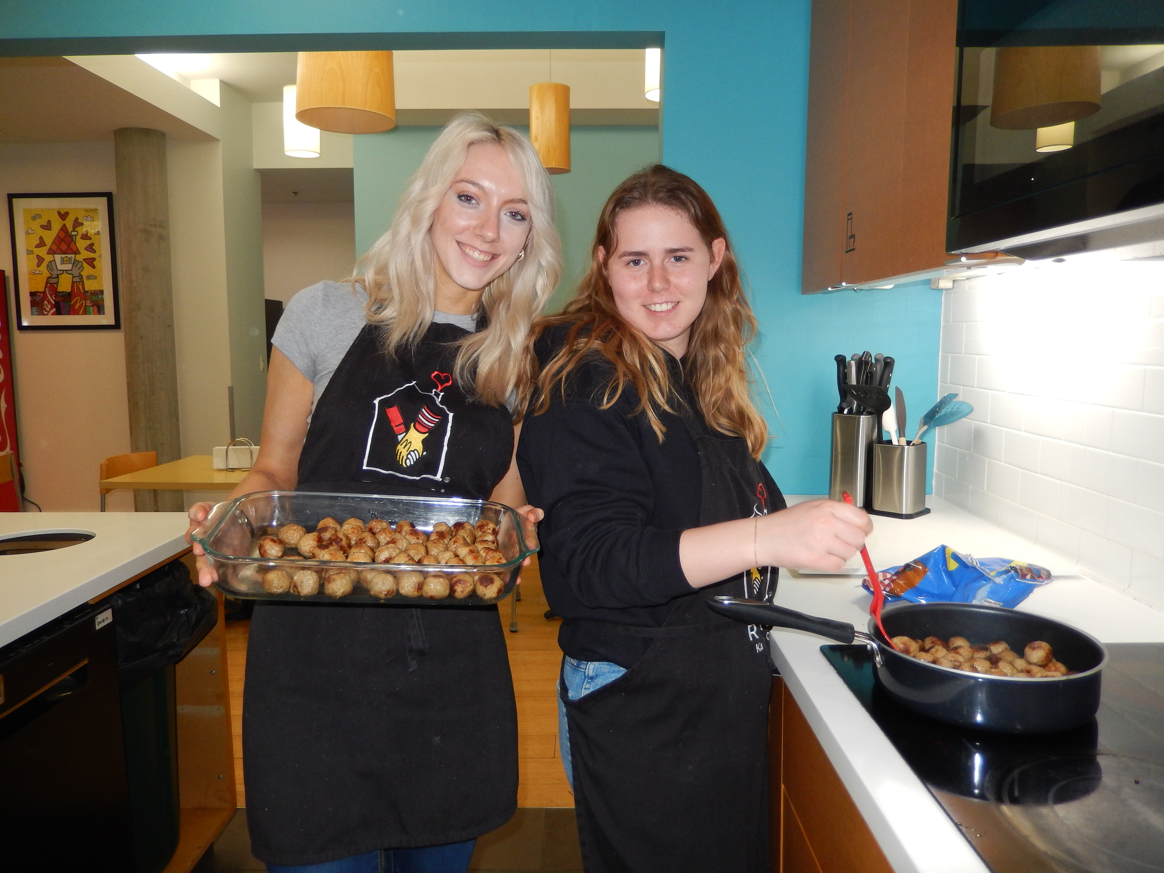 Two University of Kansas sorority sisters cook and serve food for a philanthropy event.