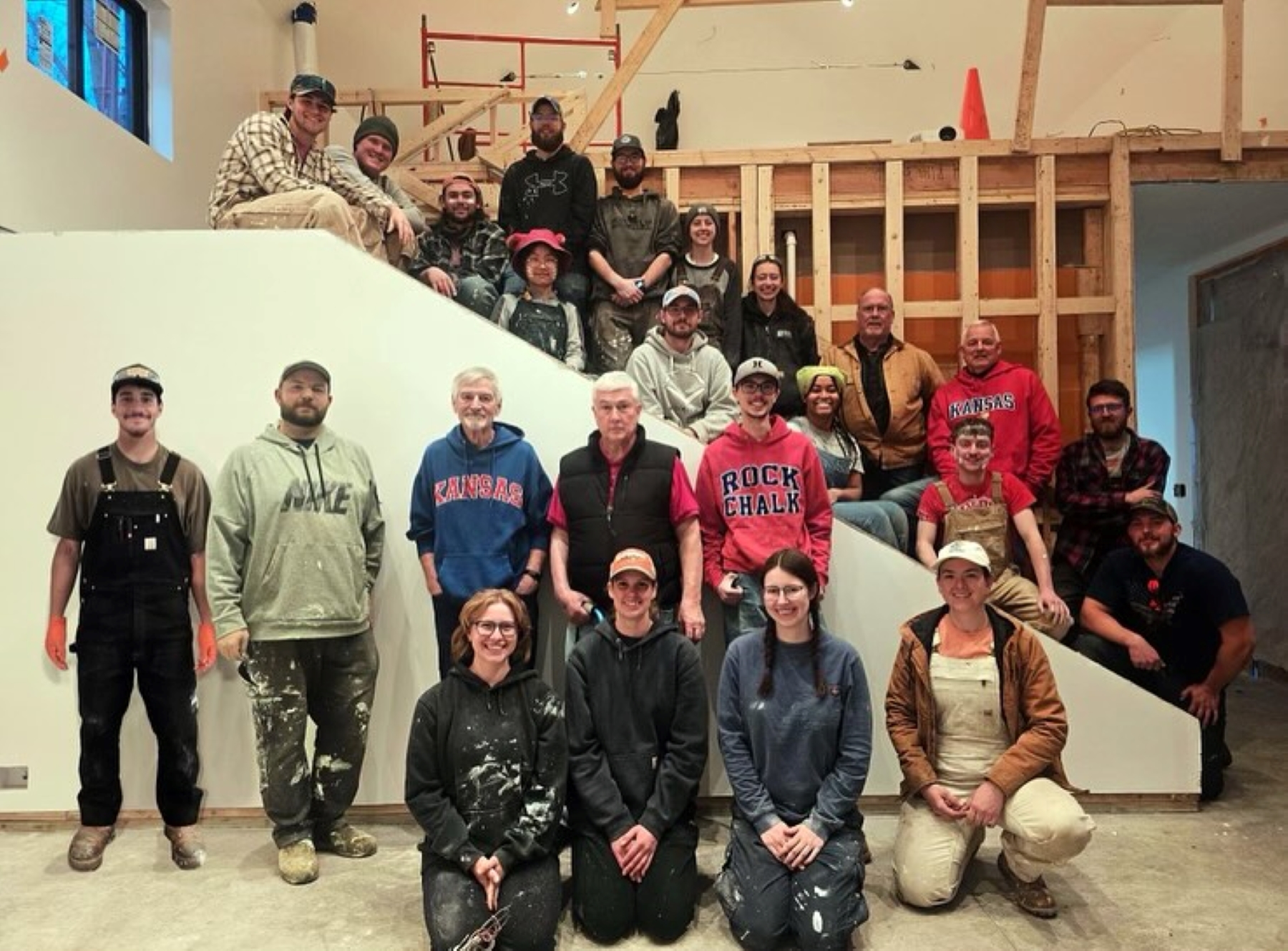 University of Kansas Studio 804 class of 2025, posing inside the kitchen of their home build project.