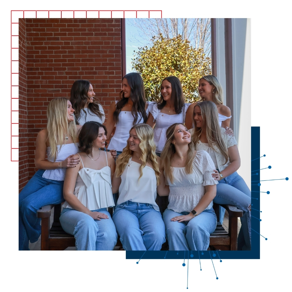 A group of sorority women at the University of Kansas pose for a portrait while dressed in white. 
