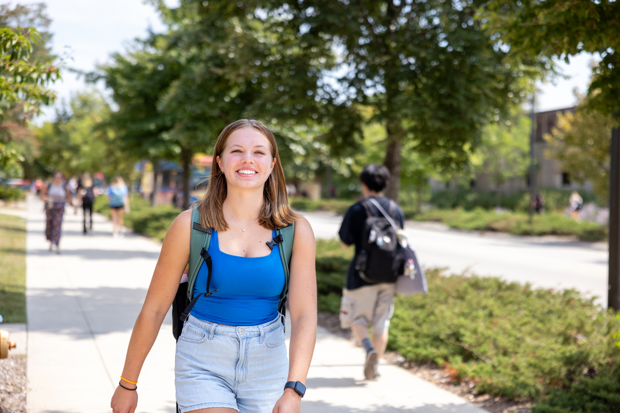 University of Kansas student Sydney Wynia walks on the KU campus and smiles at the camera.