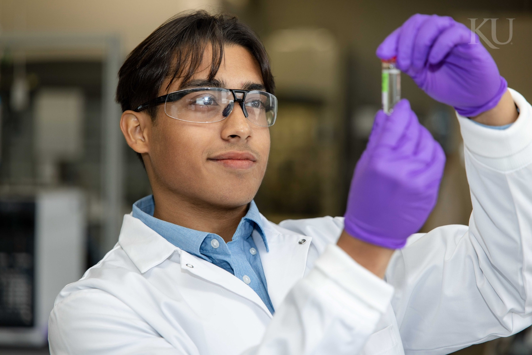 University of Kansas undergraduate researcher Pritam Ray looks at a test tube in a lab. 