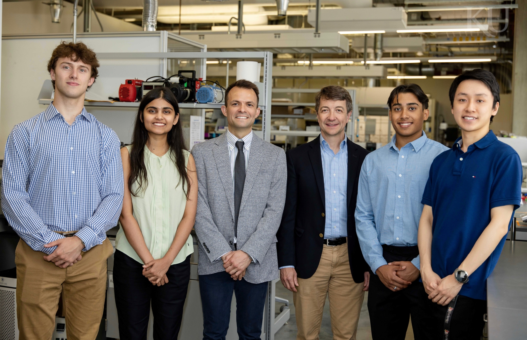 A group of undergraduate researchers at the University of Kansas pose for a photo with their faculty mentor in a lab.