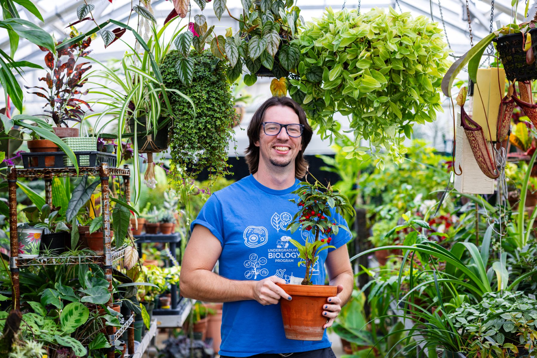 University of Kansas Haworth Hall Greenhouse Manager Dan Ruffing poses for a portrait with a plant in hand.