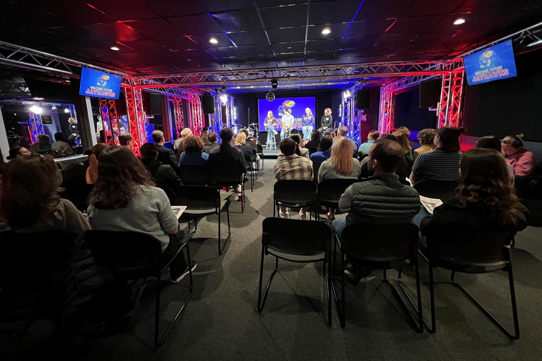 A room filled with prospective University of Kansas students at a Winter Reception event with a panel of current regional KU students.