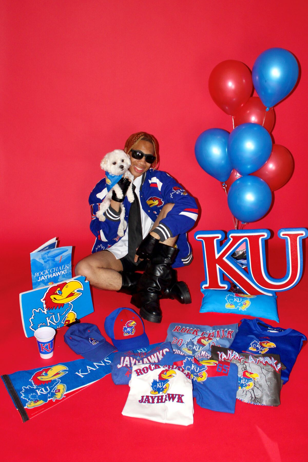 University of Kansas student Joshua Alston is shown with his dog and a variety of KU items to celebrate his admission.
