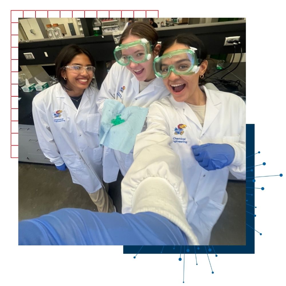 University of Kansas chemical engineering majors take a selfie in their white lab coats and goggles.