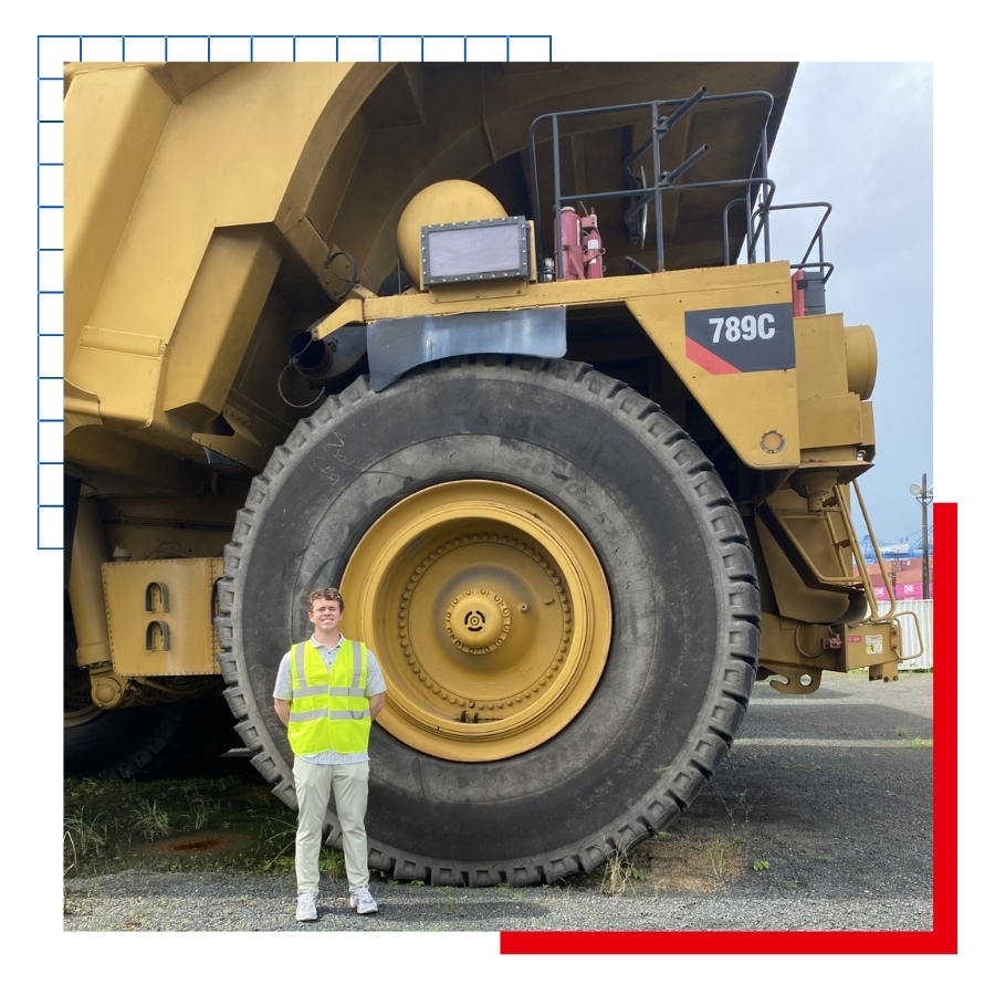 KU Supply Chain Management major Drake Schotland stands in front of a giant dump truck during a study abroad trip to Panama.
