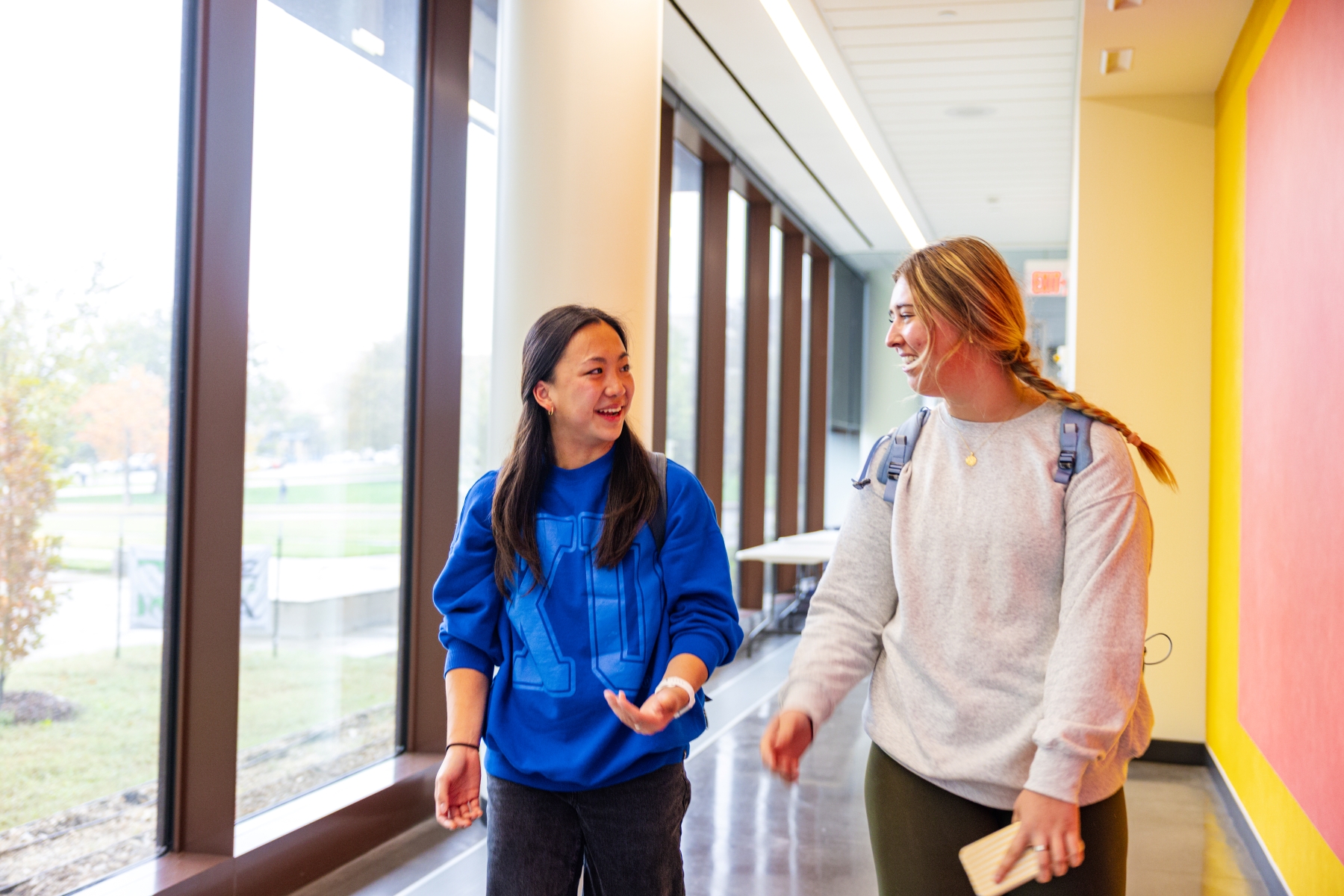 Two KU students walk down a hallway in the University of Kansas School of Business.