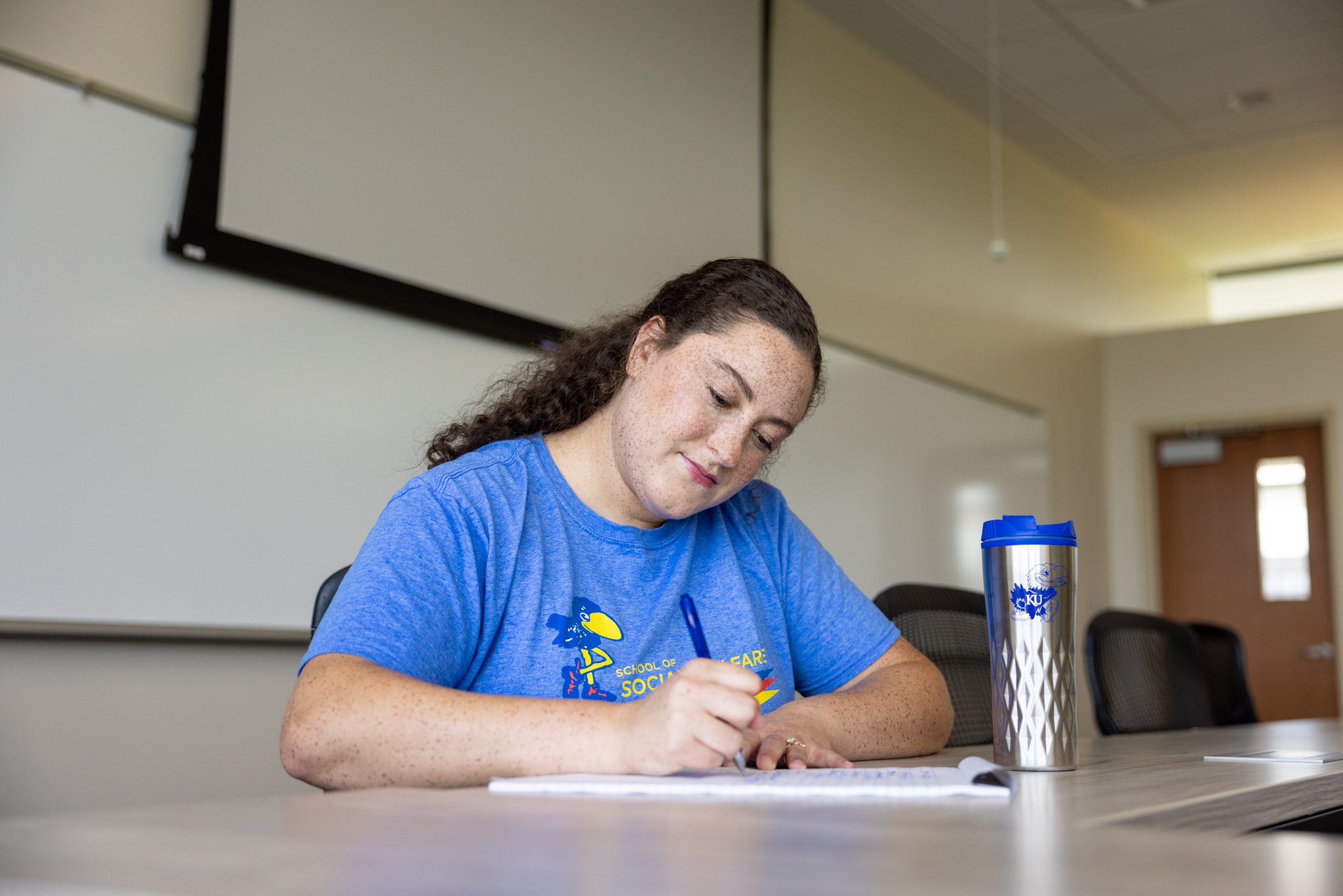A KU graduate student from the School of Social Welfare takes notes in a classroom setting.
