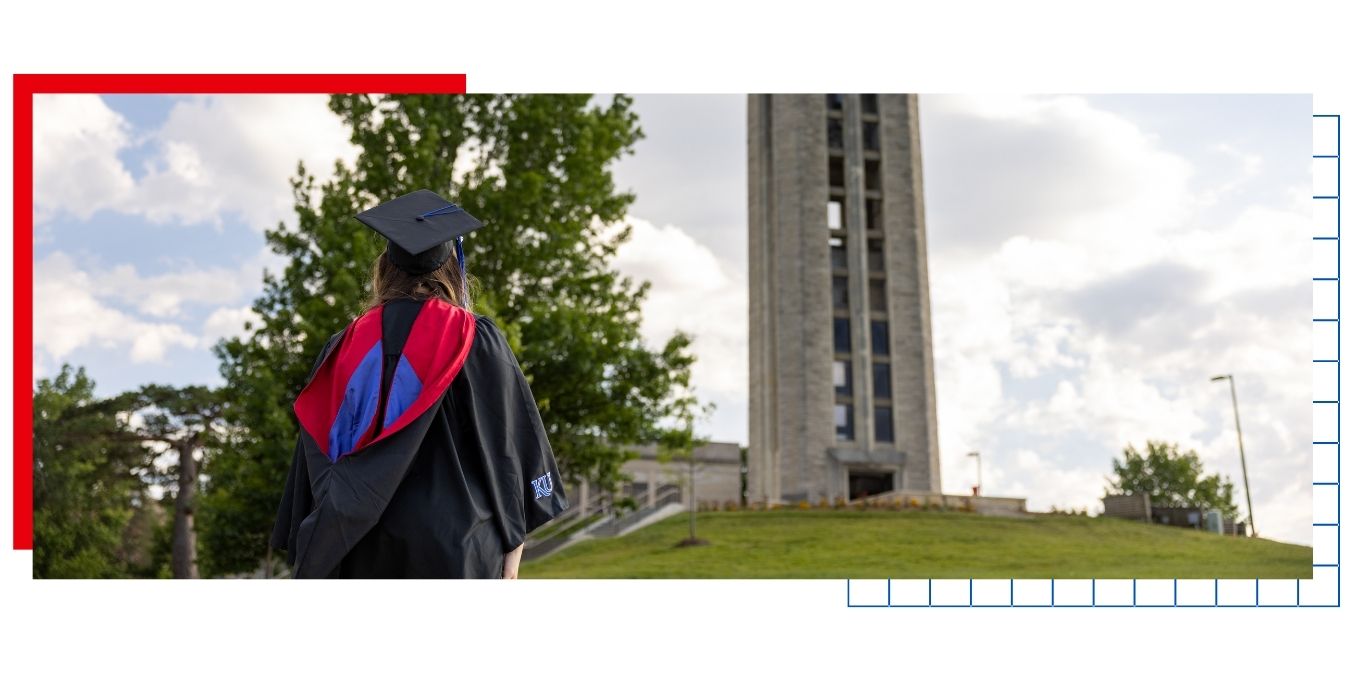 A KU graduate student in a cap and gown looks up the Hill toward the Memorial Campanile on the University of Kansas campus as part of a story explaining a Professional Degree.