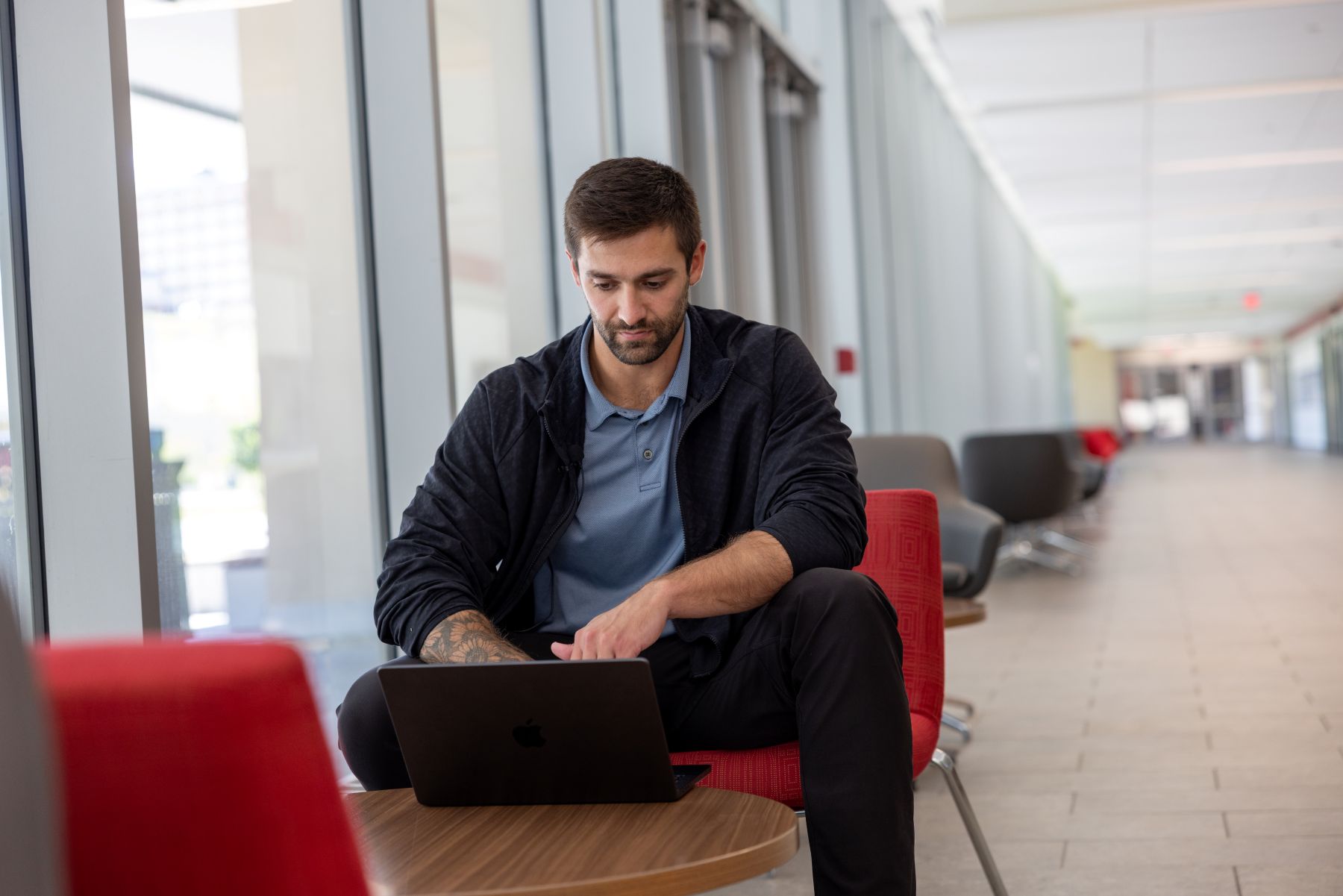 A University of Kansas graduate student studies at a laptop in the lobby of a campus building.