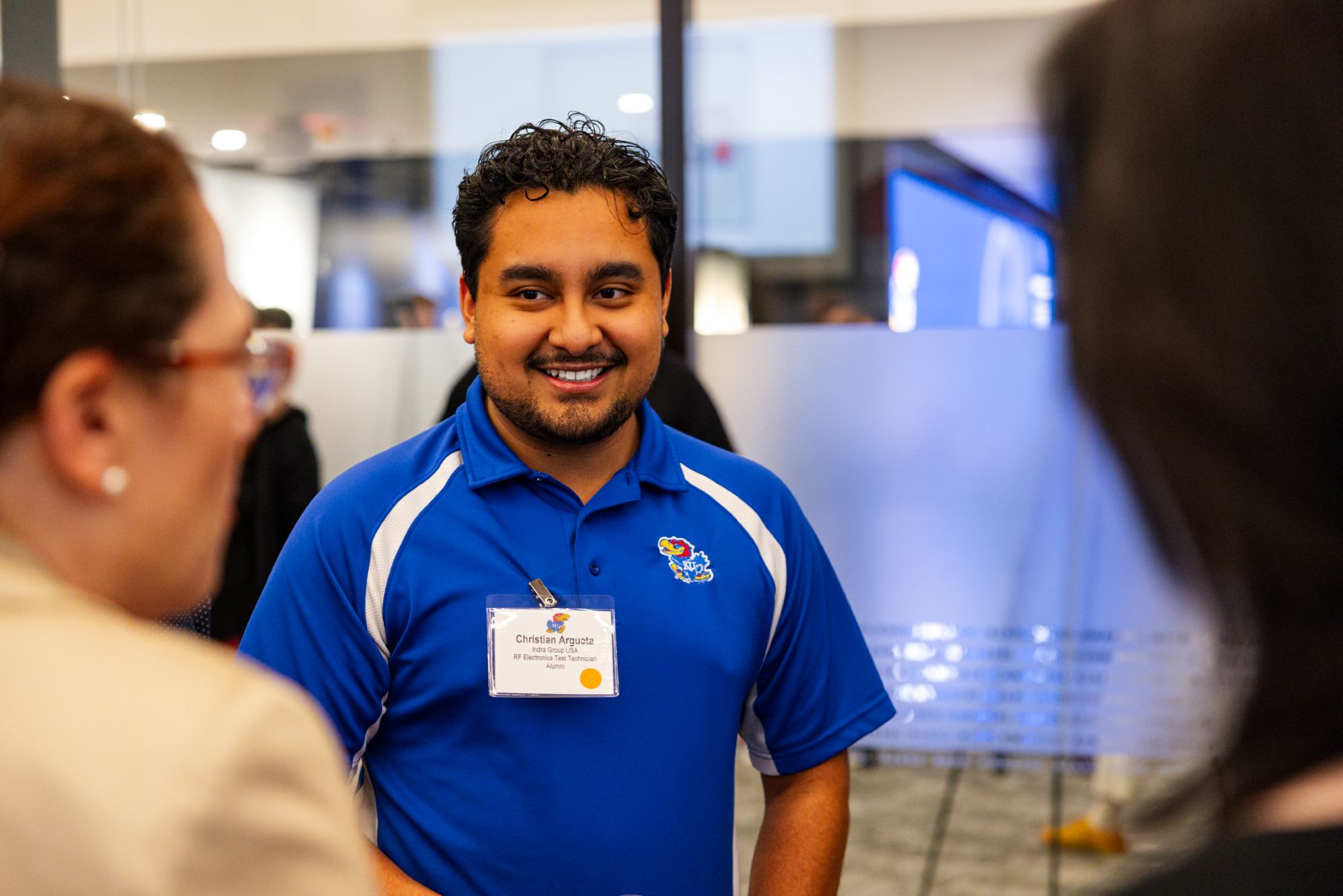 A man in a University of Kansas polo shirt smiles at a career networking event on the KU campus.