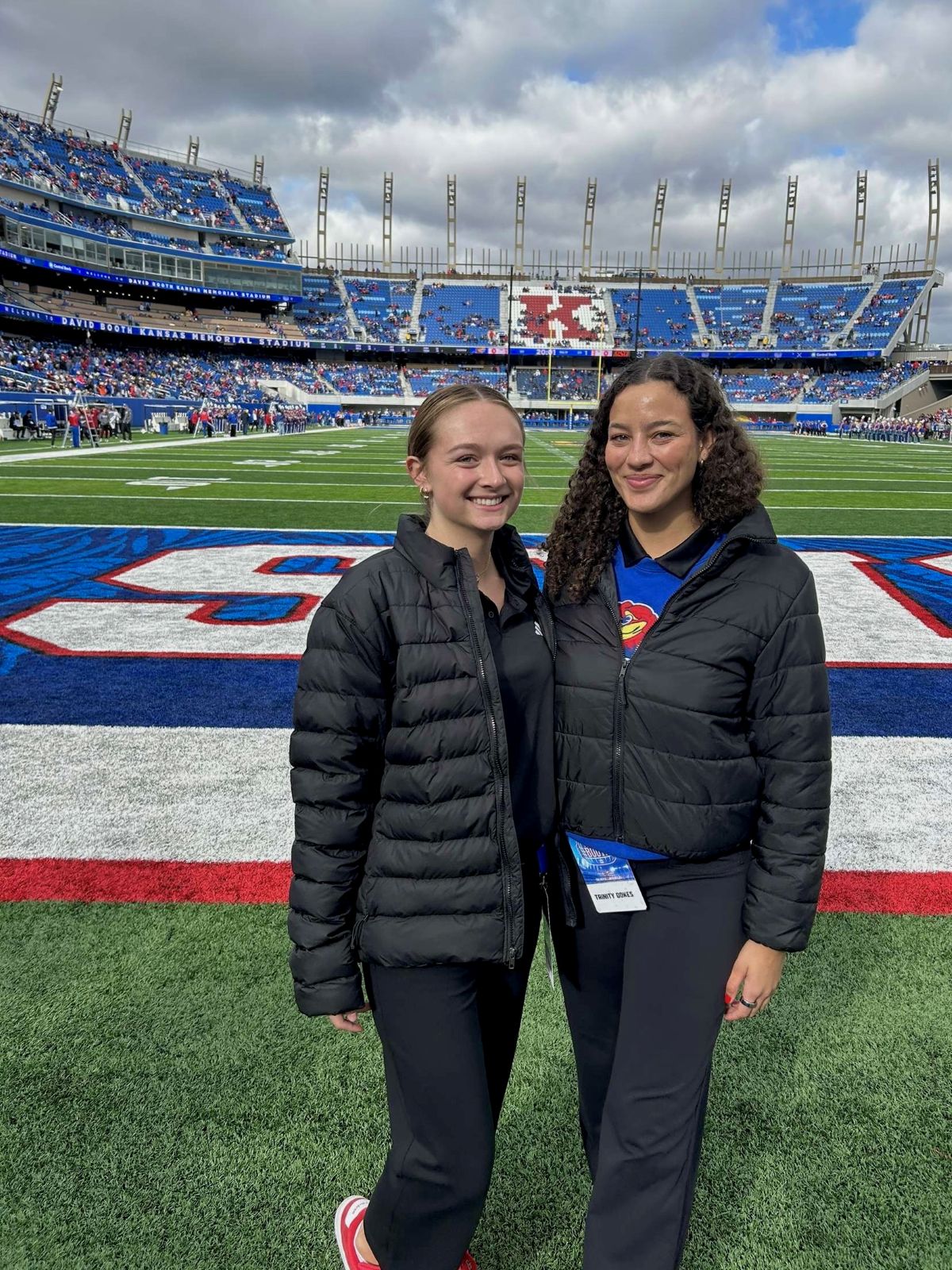 Two University of Kansas Sport Management students pose on the field at the David Booth Memorial Stadium.