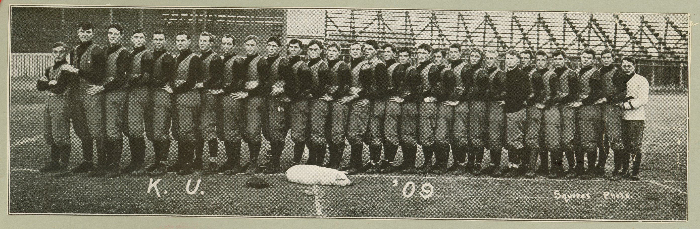 A historic image from the University of Kansas of their football team posing with a 1909 mascot, a live pig named Don Carlos.