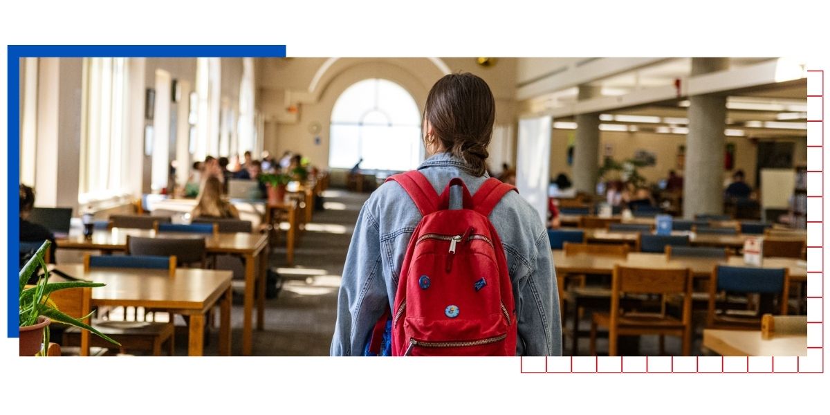 A University of Kansas walks through Anschutz Library on the KU campus with a red backpack.