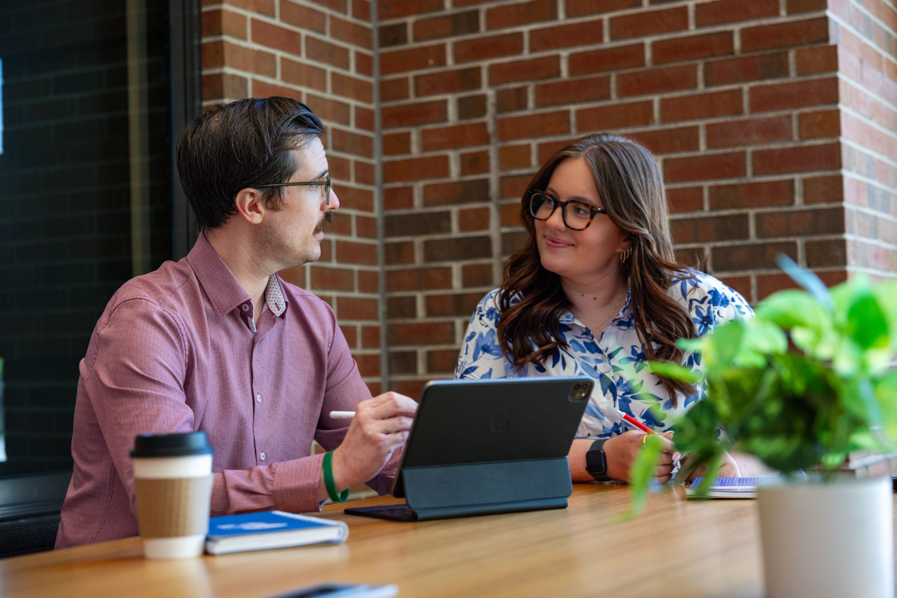 A man and woman in a business setting sit at a desk to go over tuition reimbursement policies for their company.