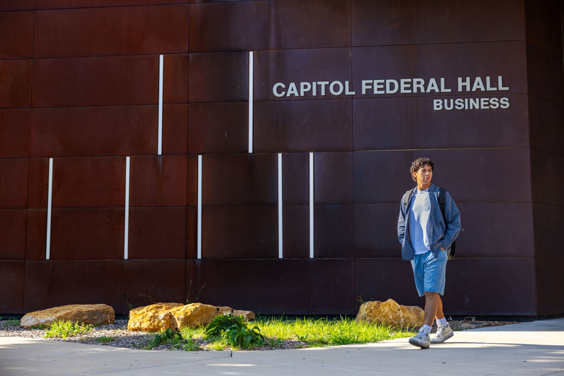 University of Kansas transfer student Steven Ibrahim walks in front of Capitol Federal Hall School of Business on the KU campus.
