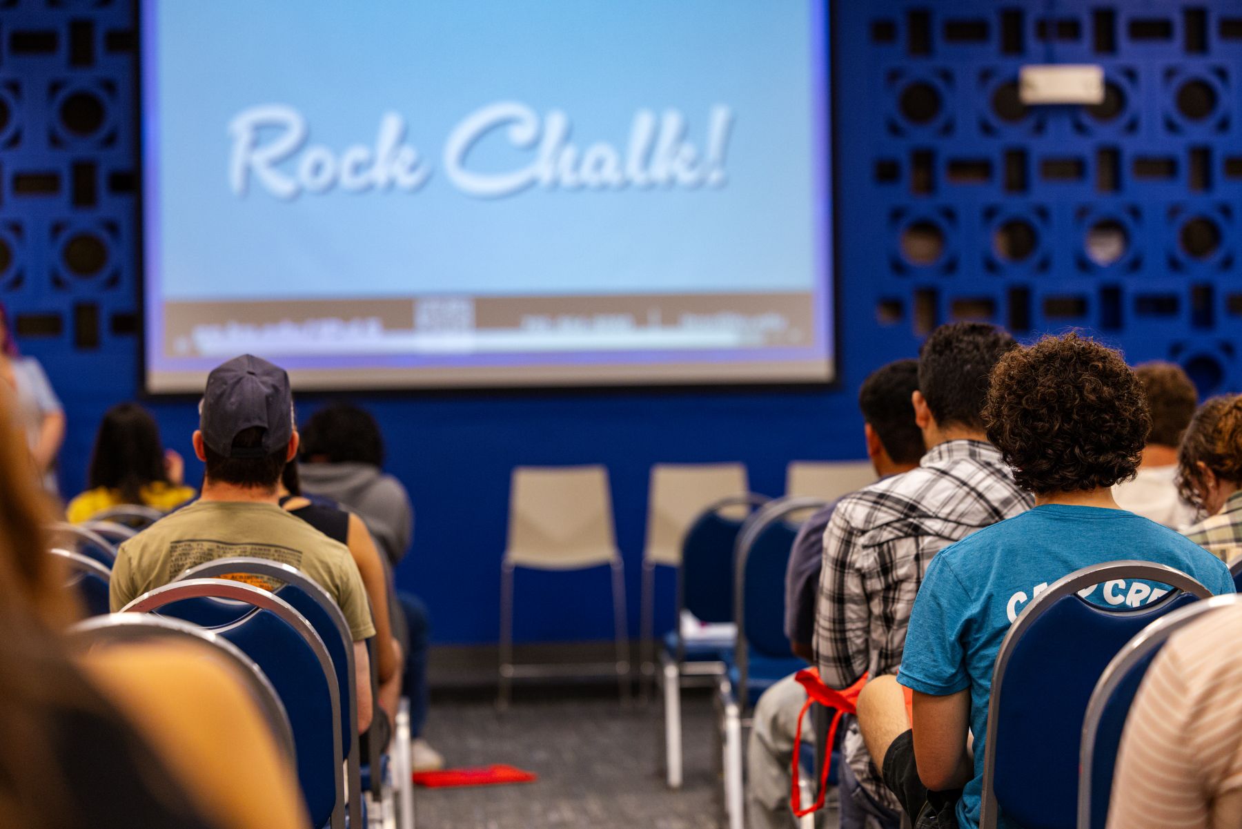A group of people in a room watching a presentation for a high school visit from the University of Kansas School of Business.