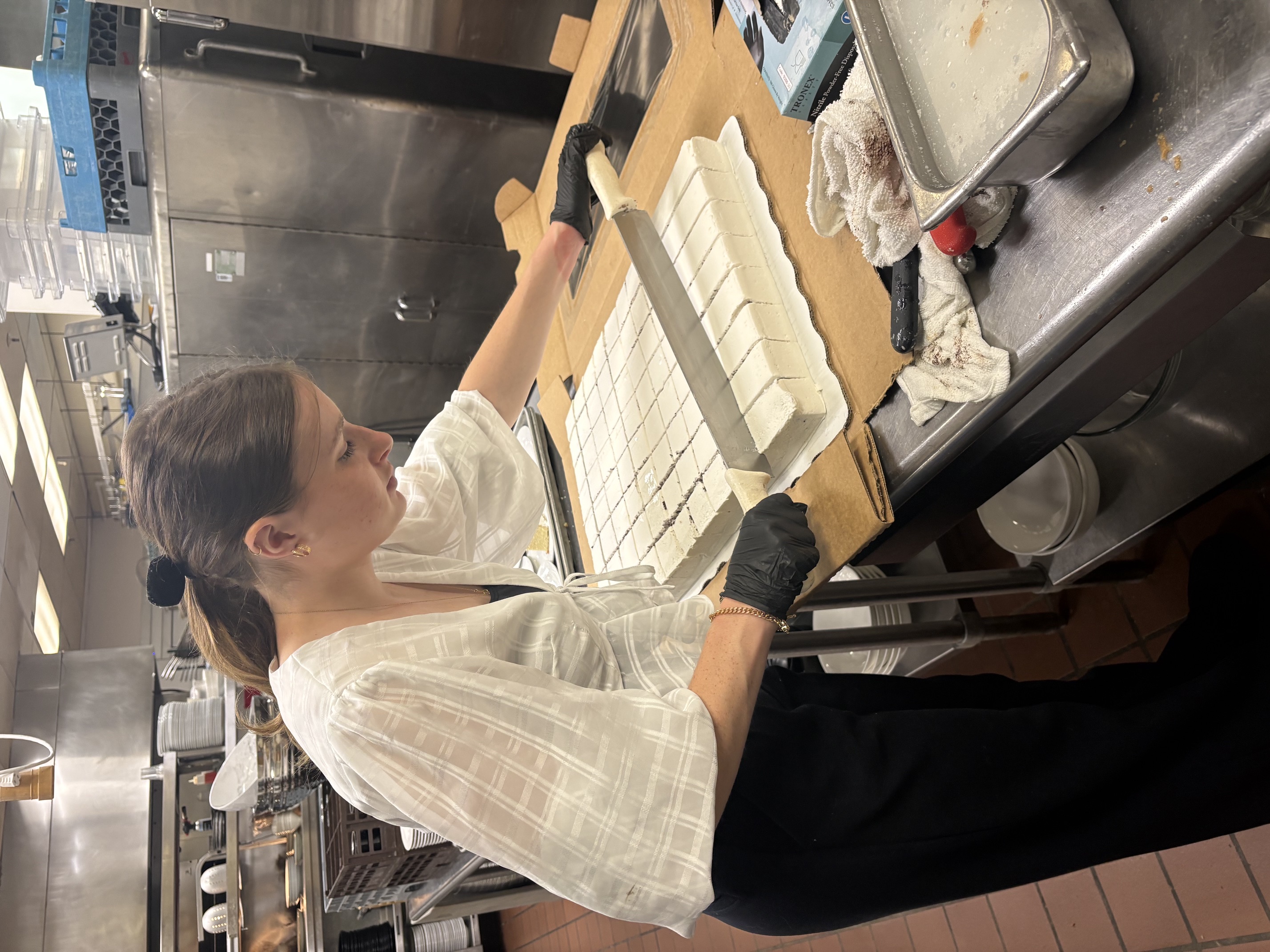 KU School of Business student Ella Hayes slices a cake during her hospitality internship at the Elms Resort and Spa.