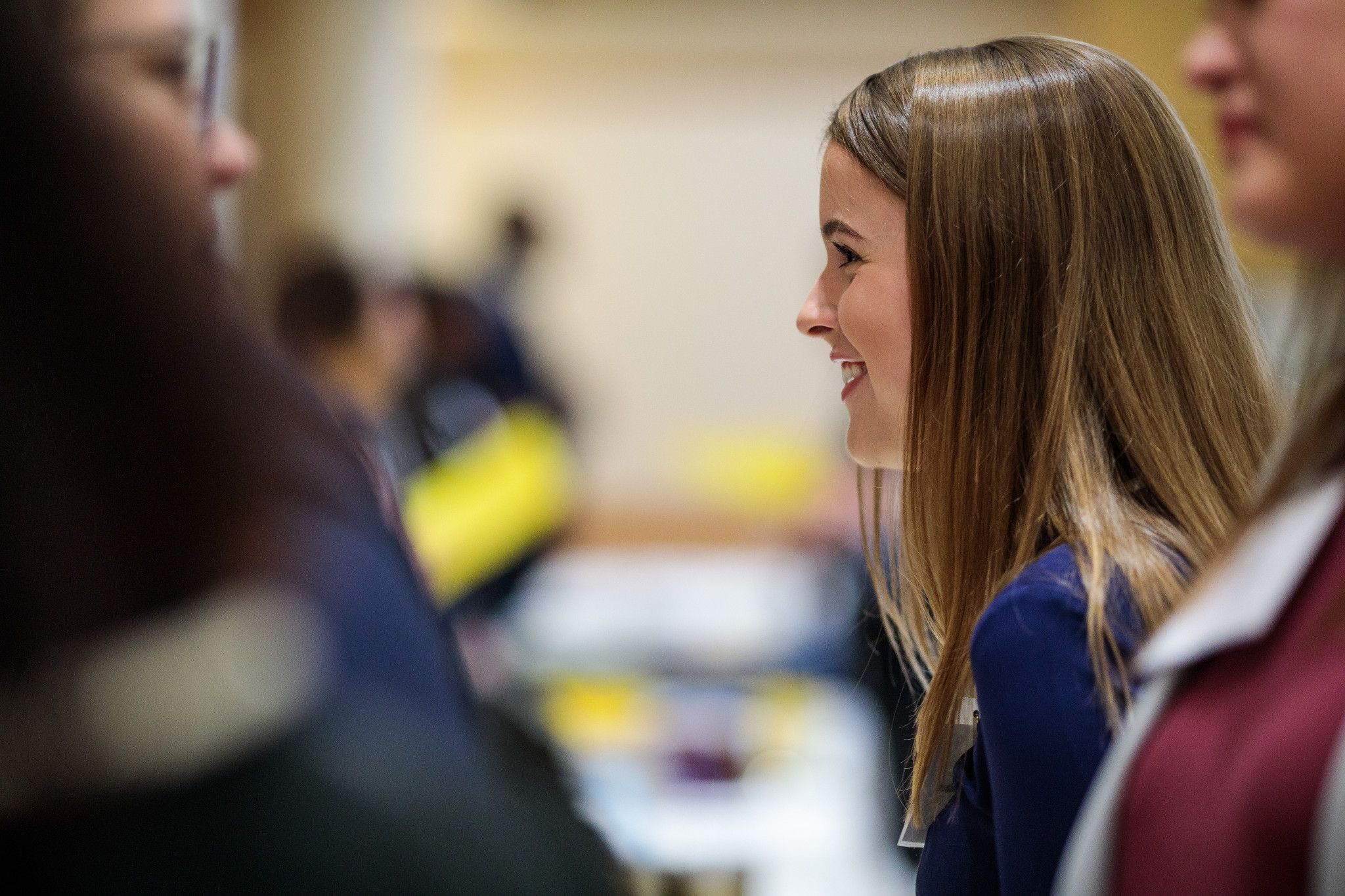 A profile view of a student smiling and in conversation at a career fair.